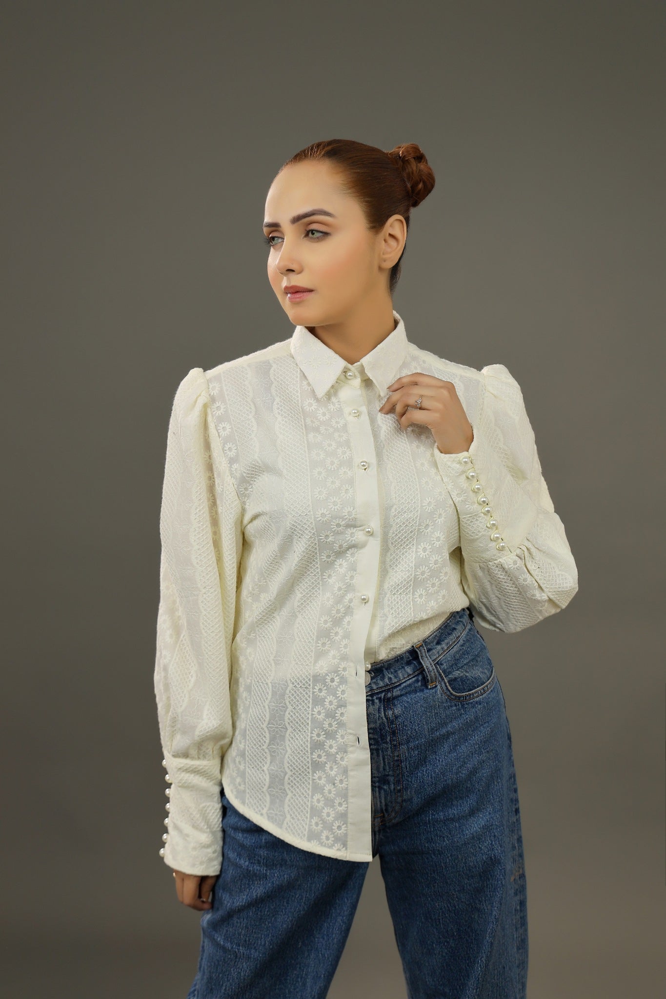 Woman wearing a white blouse with lace details and blue jeans on a gray background.-Embroidered summer-women-Shirt-Relaxed body fit-Structured collar-Pearl buttons-Unlined-Long balloon sleeve with long cuffs-Fabric: 100% Cotton blouse-frontview