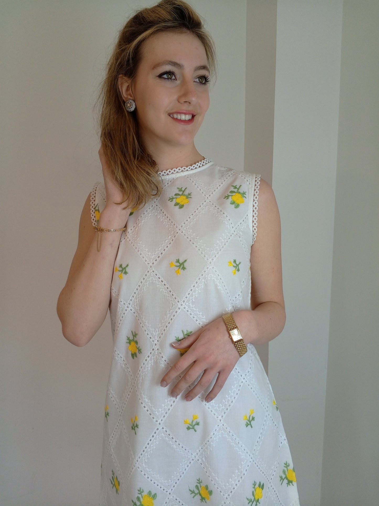 Woman wearing a white dress with yellow floral patterns against a plain background