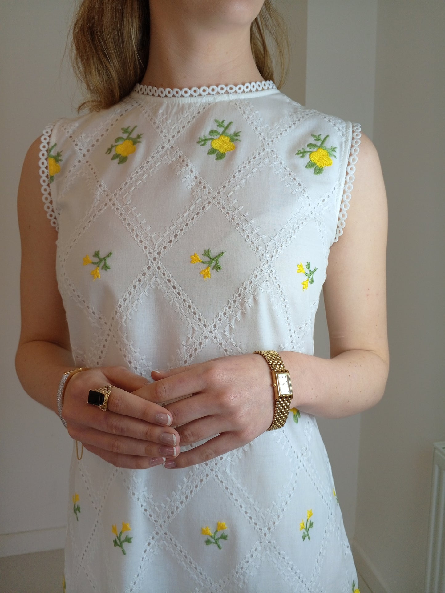 White sleeveless top with yellow floral embroidery worn by a person.