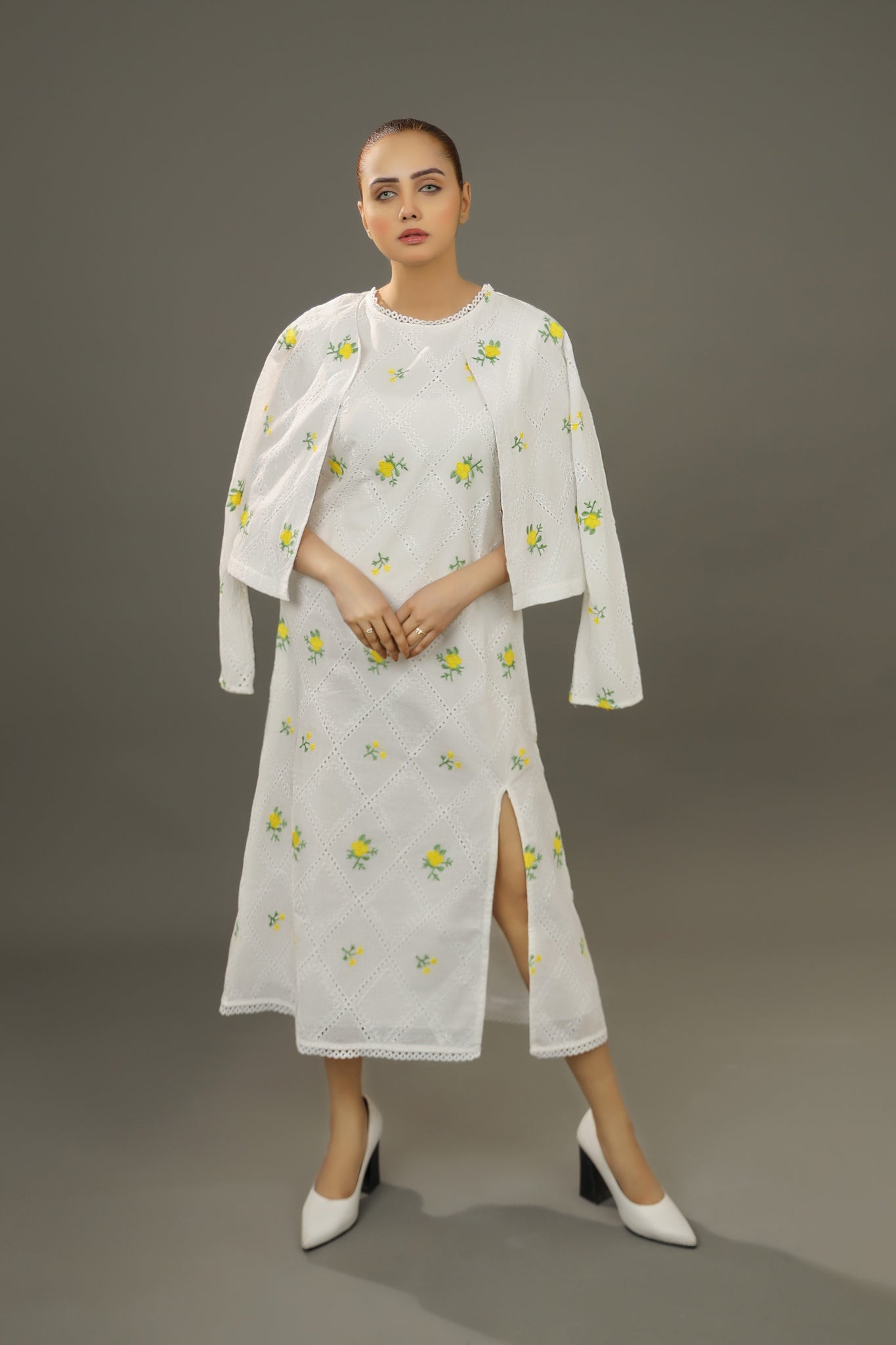 Woman wearing a white embroidered summer oraganic cotton dress with a matching jacket.