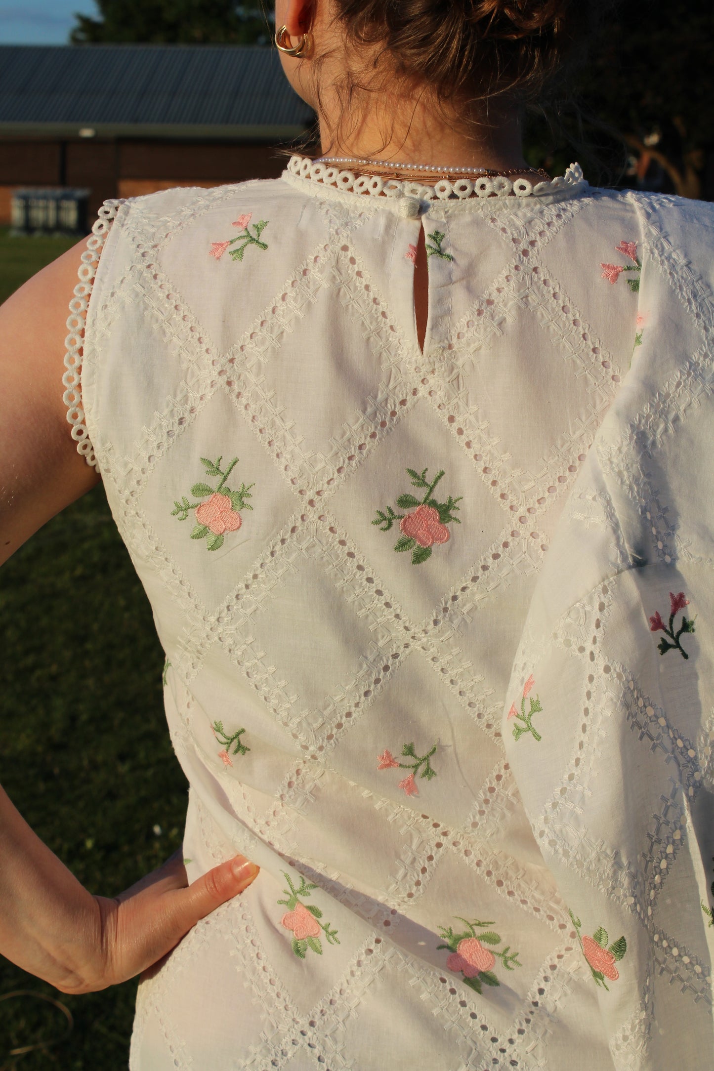 A woman is wearing a Pink and white embroidered dress-Midi length relaxed body fit-Boat neck with lace -left side leg split-full lined dress with soft 100% fine cotton -Sleeveless with lace -Fabric: 100% Cotton-closeup