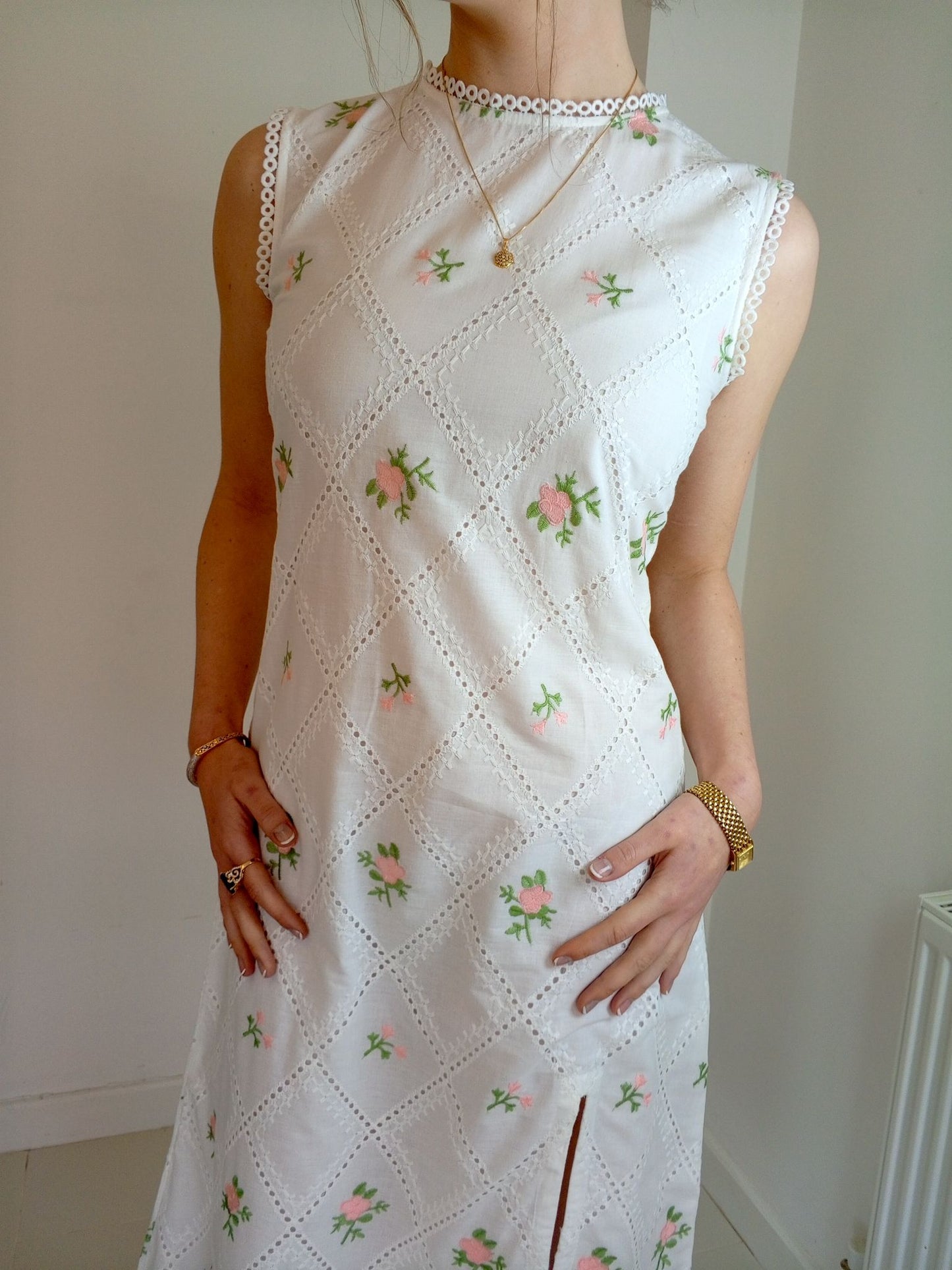 White dress with floral patterns worn by a person against a plain Pink and white embroidered dress-Midi length relaxed body fit-Boat neck with lace -left side leg split-full lined dress with soft 100% fine cotton -Sleeveless with lace -Fabric: 100% Cotton