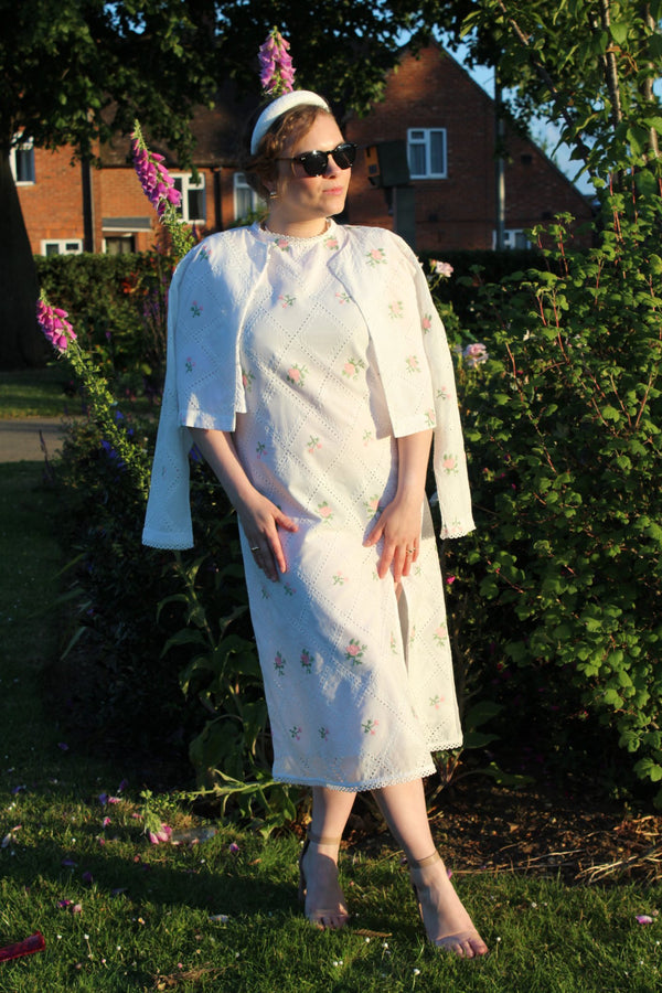 woman wearing a white dress with floral patterns and a matching jacket outdoors.frontangle