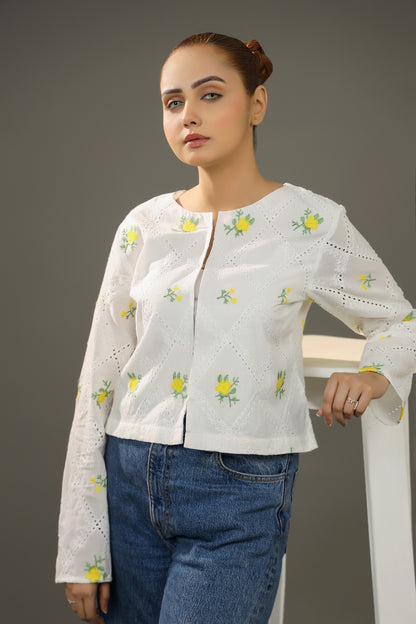 Woman wearing a white embroidered blouse with blue jeans against a gray background. Cropped yellow embroidered cardigan-Relaxed body fit-Round neck-Inside hidden hook closure-full lined body-Long sleeves with lace -Fabric: 100% Cotton