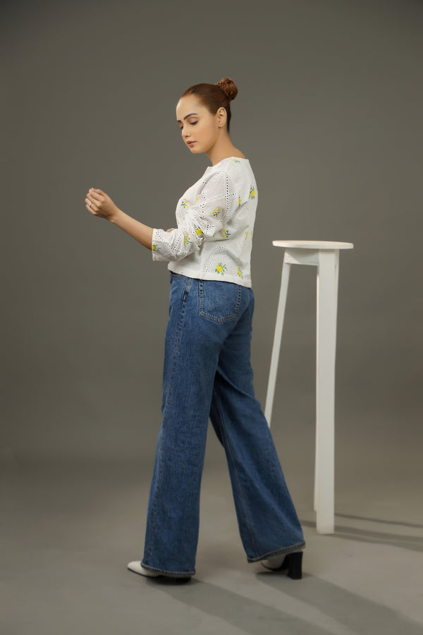 Woman wearing a white floral sweater and blue jeans standing against a gray background. Cropped yellow embroidered cardigan-Relaxed body fit-Round neck-Inside hidden hook closure-full lined body-Long sleeves with lace -Fabric: 100% Cotton blouse