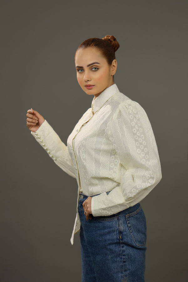 Woman wearing a white embroidered blouse and blue jeans against a gray background.-Embroidered  summer-women-Shirt-Relaxed body fit-Structured collar-Pearl buttons-Unlined-Long balloon sleeve with long cuffs-Fabric: 100% Cotton