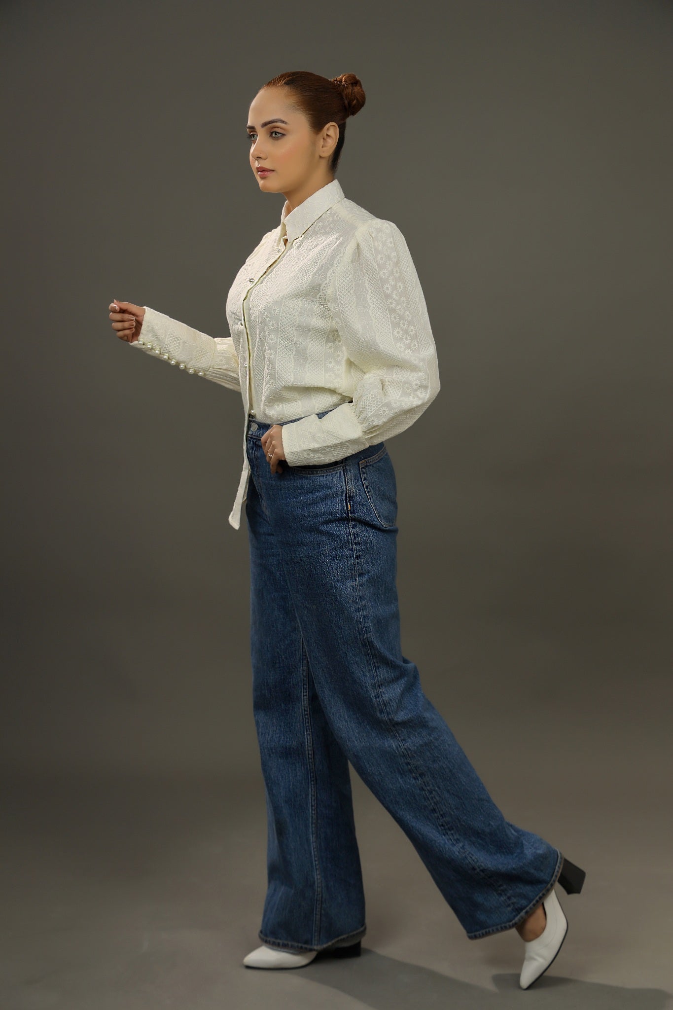 Woman wearing a white blouse and blue jeans on a gray background.-Embroidered  summer-women-Shirt-Relaxed body fit-Structured collar-Pearl buttons-Unlined-Long balloon sleeve with long cuffs-Fabric: 100% Cotton blouse-sideview