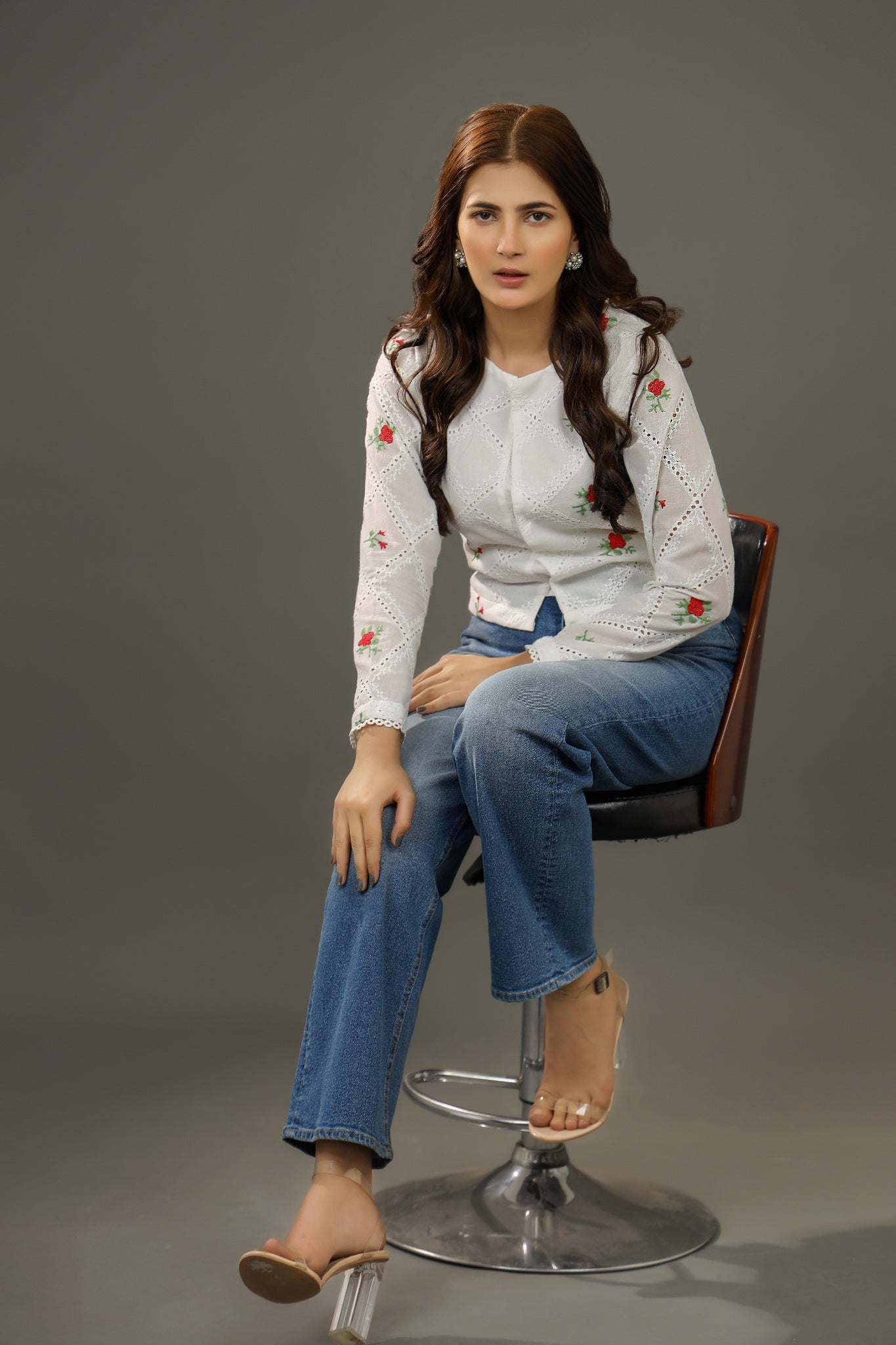 Woman sitting on a chair wearing a white blouse with floral patternsPremium-organic-cotton-summer-woman-top-floral-red-embroidery-fullsleeve blouse